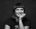 Coach Mar A smiling woman with short, dark hair wearing a black shirt against a dark background.