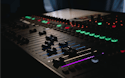 IM Info Tablero de mezcla de sonido oscuro con botones iluminados de varios colores.